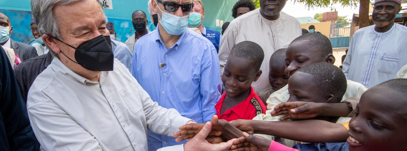 UN Secretary-General greets children while surrounded by people of all ages