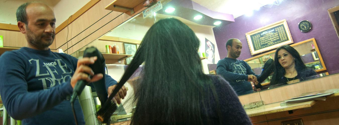 a man blow dries a woman's hair in a salon