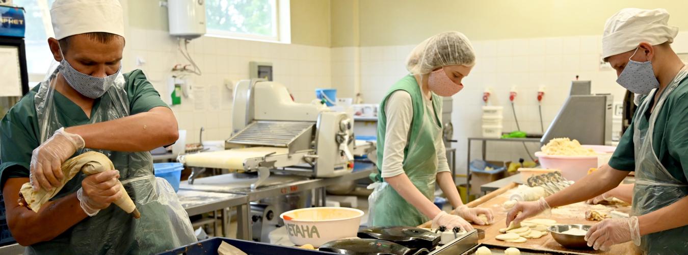 two men and a woman baking in a kitchen