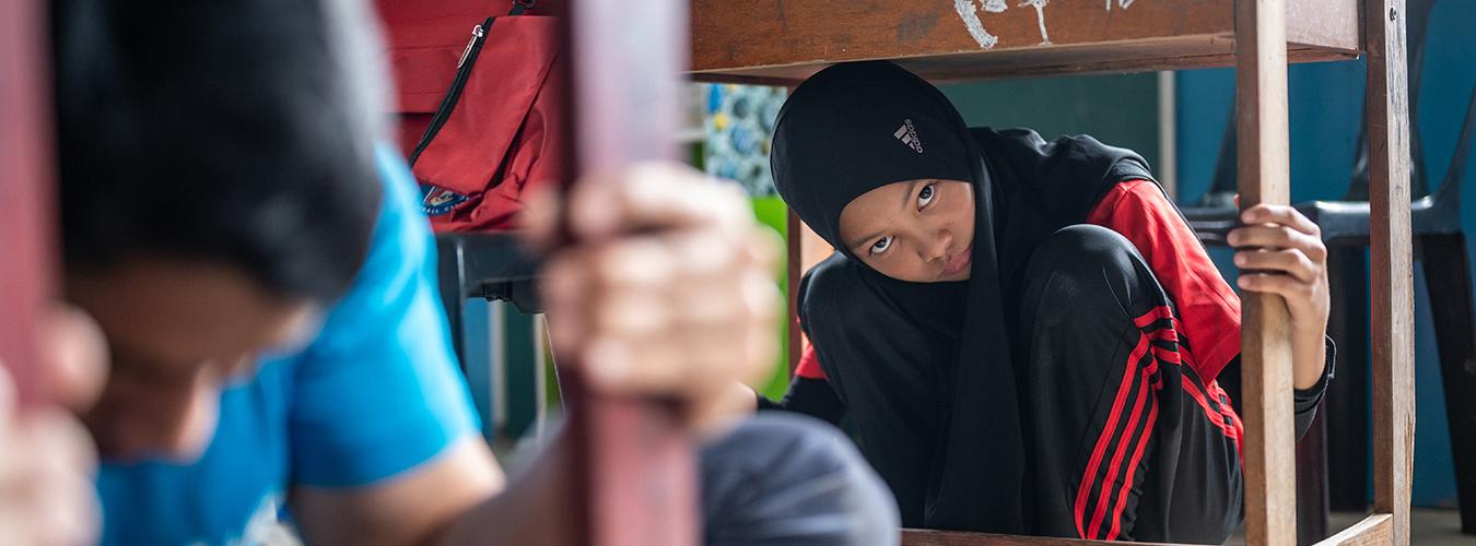 Unos estudiantes debajo de sus pupitres en una simulación de cómo actuar ante un terremoto