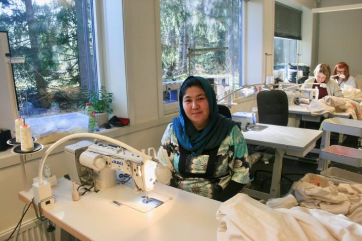 Trabajadora sonriendo a cámara frente a su máquina de coser