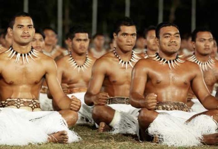 men in indigenous dress sitting cross-legged