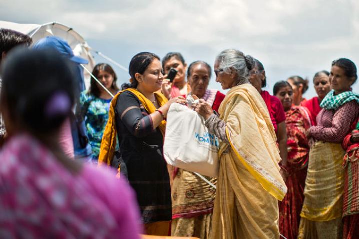 A woman gives a bag to other woman in front of a group gathered