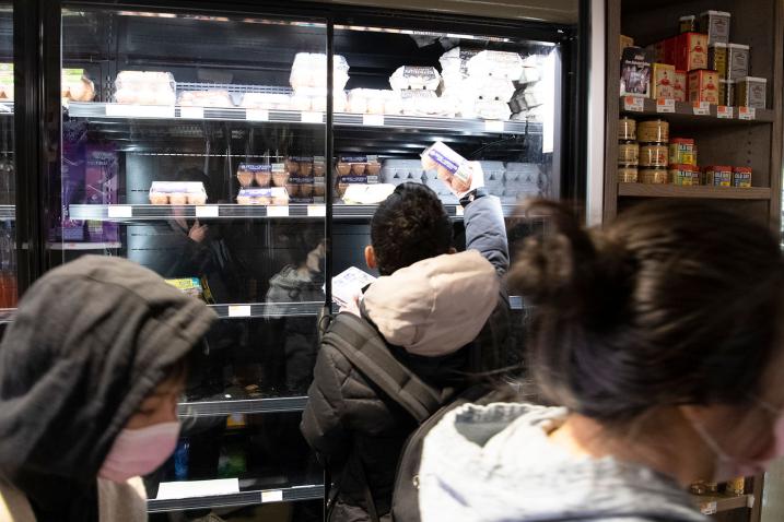 A scene inside a grocery store shows isles with shoppers choosing items whilst wearing face masks.