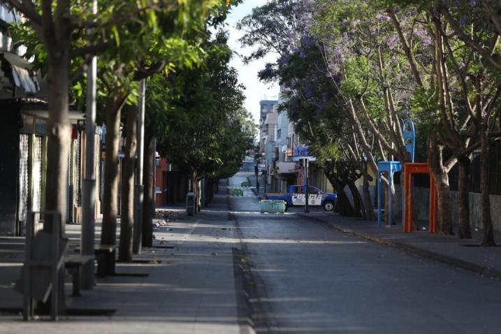 An empty city street with a Police car in view at an intersection.