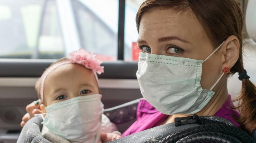 Mother and daughter wearing masks in taxi.