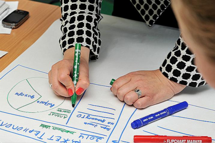 Des mains réalisant un schéma sur du papier