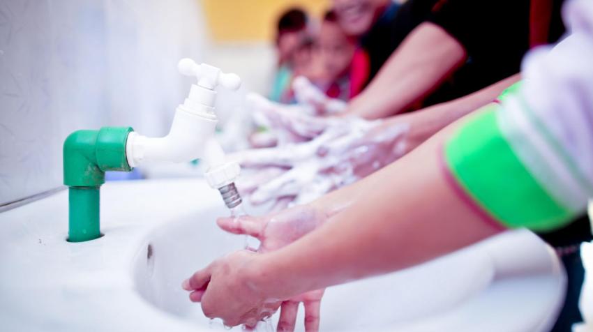 Primer plano de unas manos de unos niños lavándose las manos. 
