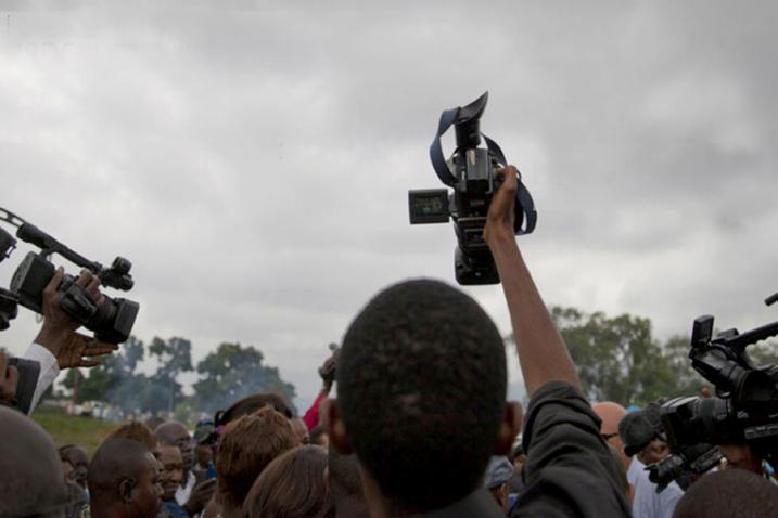 People hold cameras above a crowd. 