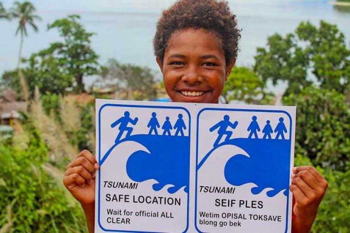 Un enfant montre une pancarte de prévention aux tsunamis.