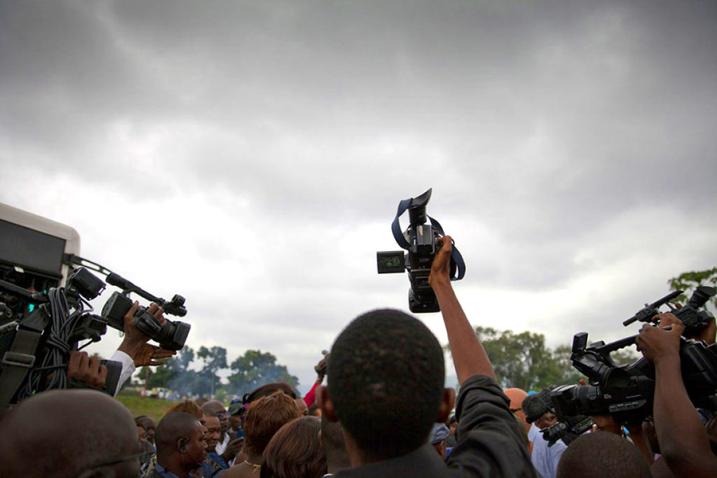 Un journaliste lève sa caméra vidéo au-dessus de la foule.