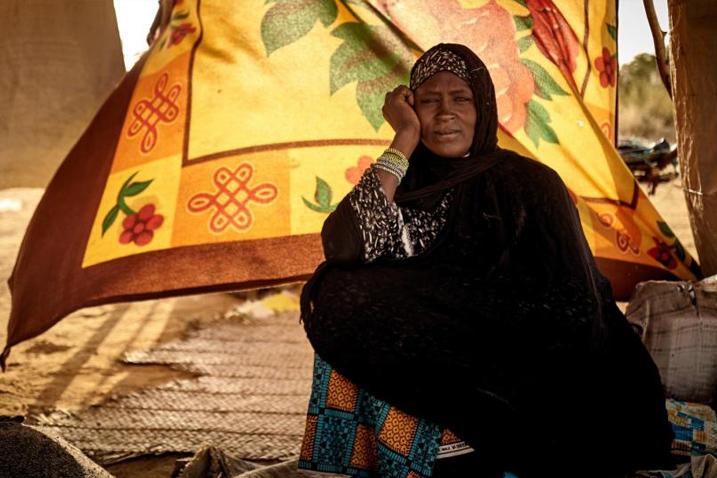 A woman sitting on the ground inside a tent.