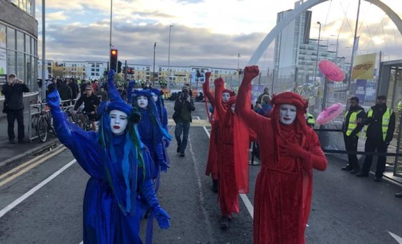 Protestors in red and others in blue costumes marching the streets