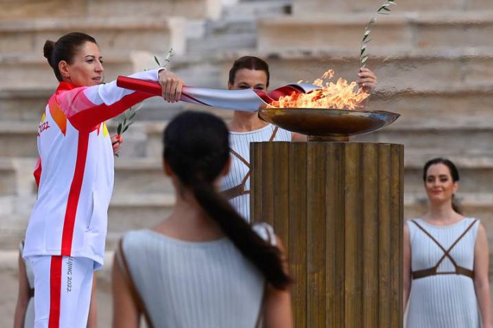 A woman in front of the podium lighting the Olympic flame