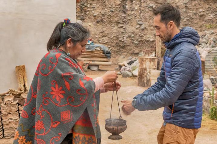 A tourist shreds medicinal herb into a pot held by Celestina.