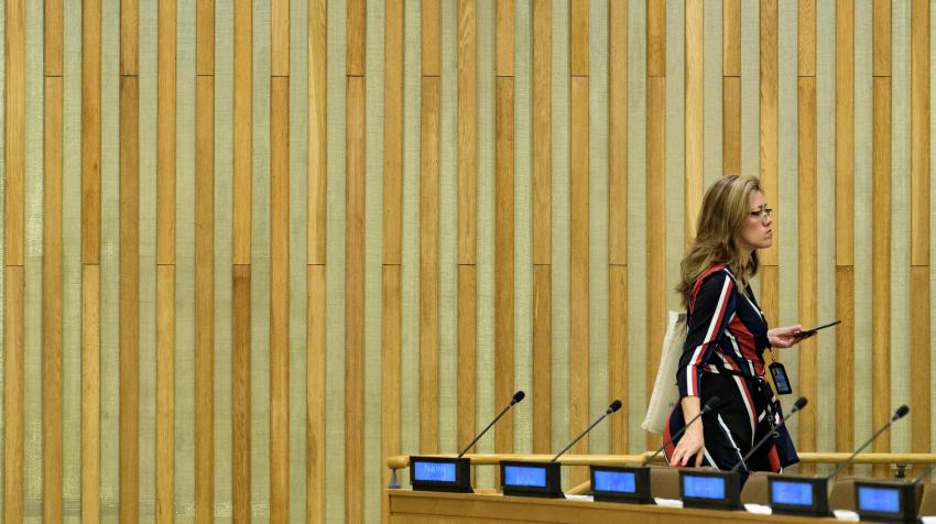 A UN Staff member standing next to desks in a meeting room.