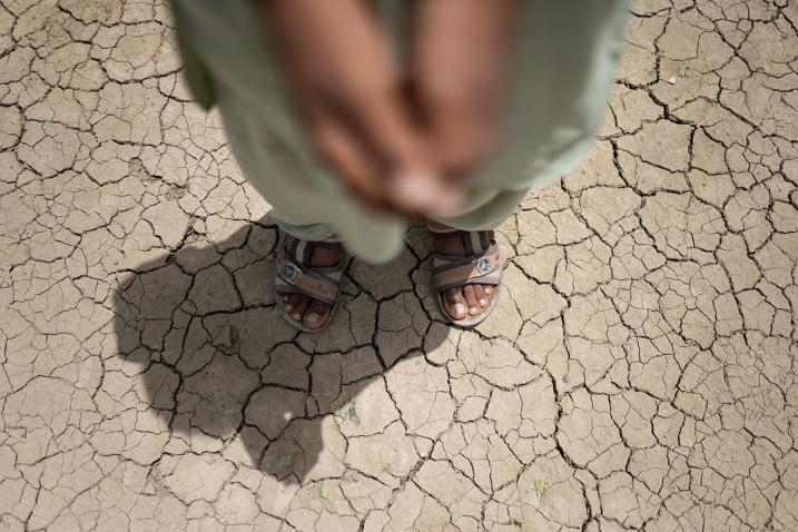Pieds d'un enfant sur un sol craquelé par la sécheresse