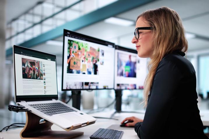 A young female journalist writing news article on her laptop.