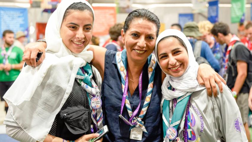 Najat poses with two girls at a conference setting