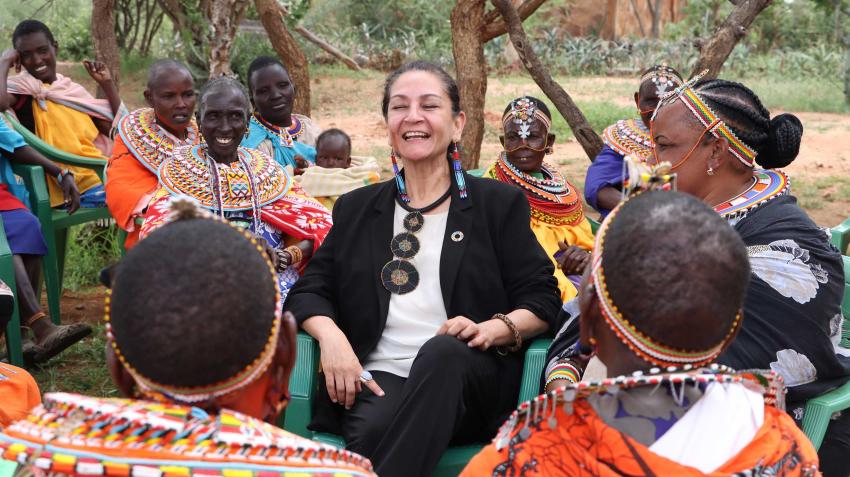 Reena sits in the midst of african women all wearing colorful clothes and looking happy