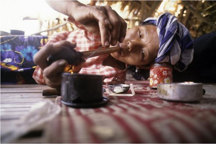 Woman smoking opium while lying down, Ban Yang, Thailand