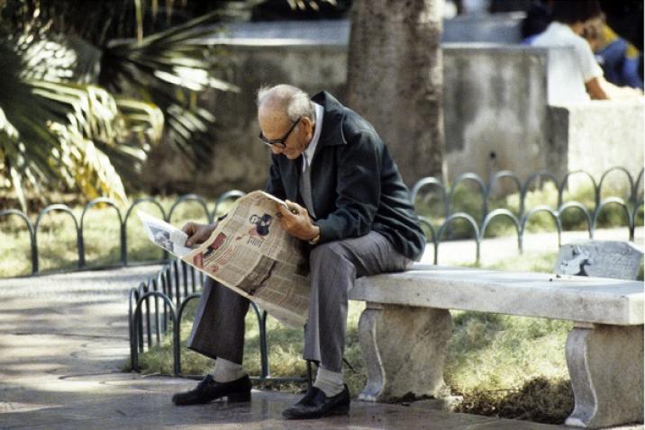 Un homme âgé lit un journal assis sur un banc à la Havane, Cuba.