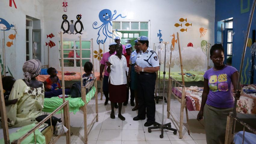 Vuniwaqa in discussion with others inside a hospital room with drawings on the walls