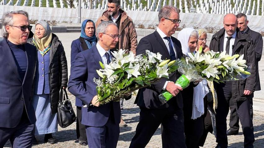 With other representatives, Serge Brammertz lays wreaths of white flowers at the memorial center