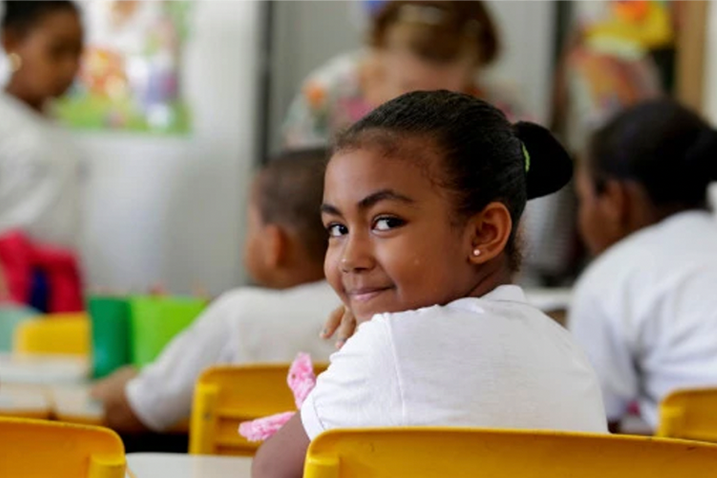 young girl smiling at desk in school