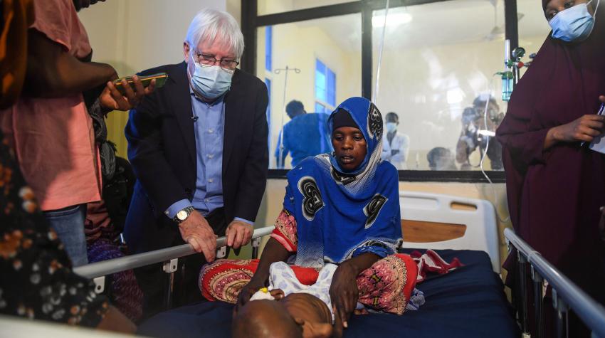 A photo of UN Humanitarian Chief, Martin Griffiths, visiting Banadir. He looks at a children laying on a hospital bed, together with a woman.