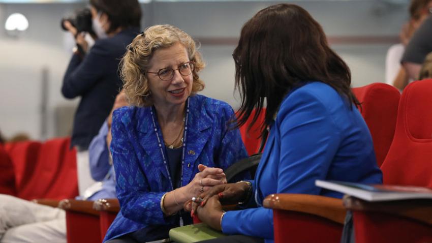 A photo of Inger Andersen speaking seated in a conference room, in a conversation with another person