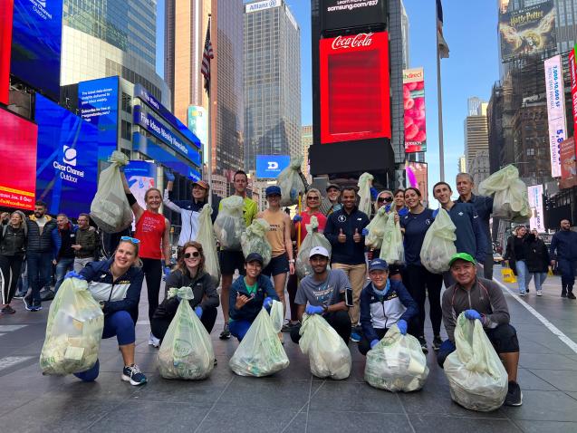 Corredores en Times Square, Ciudad de Nueva York, con bolsas de basura recogida durante el evento. Tina Muir, Directora Ejecutiva de Running for Real, es la cuarta desde la izquierda. 4 de noviembre de 2022. Cortesía de Tina Muir.