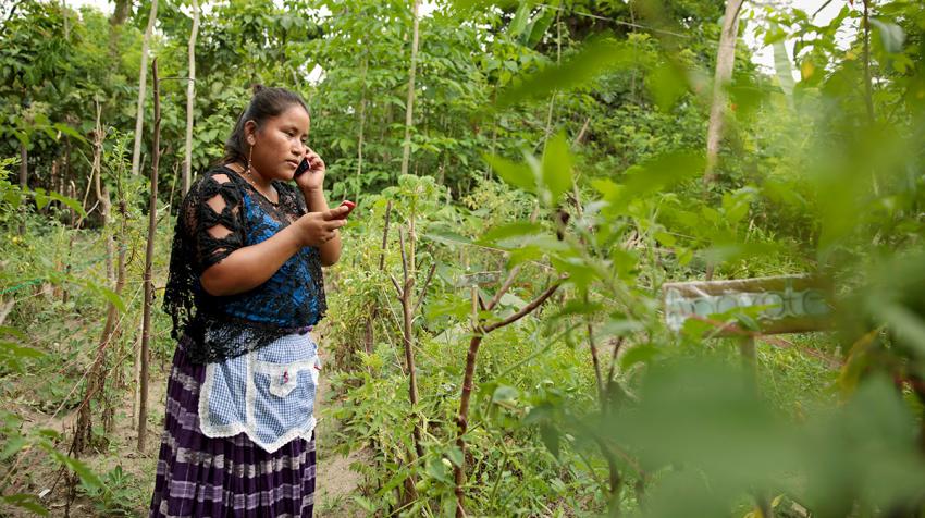 Elena Sam Pec takes a call on one phone while checking a text message on another in Puente Viejo, Guatemala, a mostly agrarian indigenous community that relies on wooden canoes to transport products and access services. UN-Women/Ryan Brown