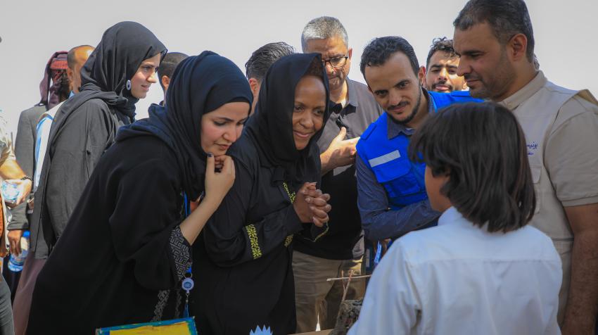 2022年10月，主管人道主义事务助理秘书长兼紧急救济副协调员乔伊斯•姆苏亚（中）在也门阿尔苏米亚境内流离失所者营地的阿尔纳赛尔学校参加活动。人道协调厅/YPN