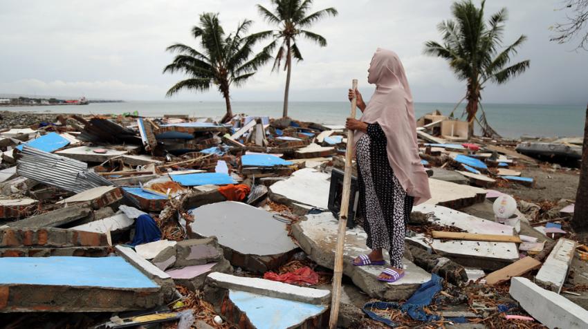 Женщина стоит на обломках рухнувших зданий в рыбацкой деревне Мамборо (Центральный Сулавеси, Индонезия) после землетрясения и цунами 2018 года. Фото: УКГВ/Энтони Берк
