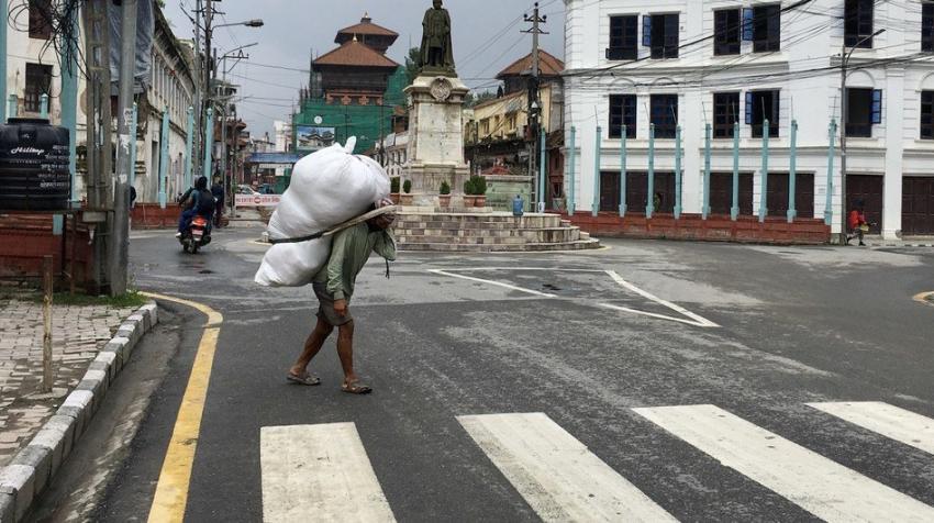 UN News\Vibhu Mishra. A daily-wage earner carrying goods on his back at a market in Nepal.