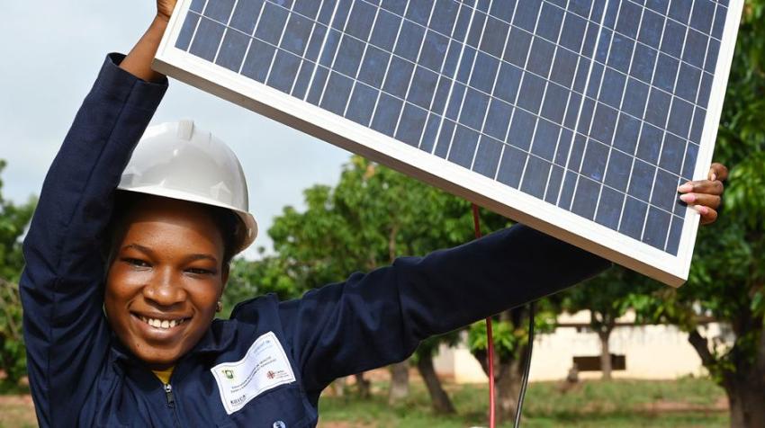 © UNICEF/Frank Dejongh. A teenage woman in Côte d'Ivoire holds up a solar panel which she is studying as part of a renewable energy course.