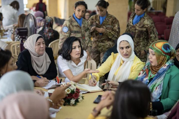 A photograph showing several women seated around a round table in discussion
