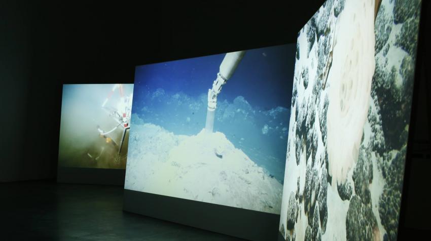 Three large screens showing scenes of climate. 