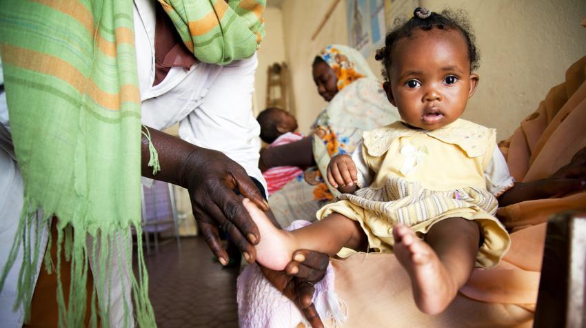 A physiotherapist massages six-month-old baby girl. 