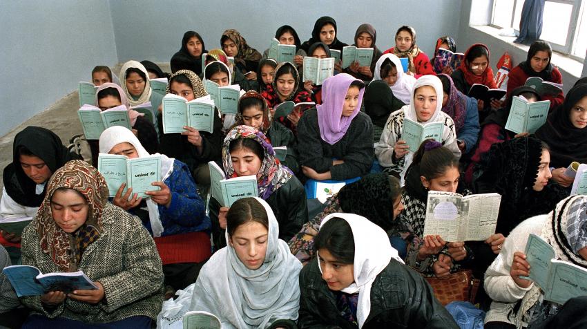 Several girl students are reading textbooks at a school in Afghanistan, where UNICEF supplies educational supplies, teachers' training, and assists in repairing infrastructure. 