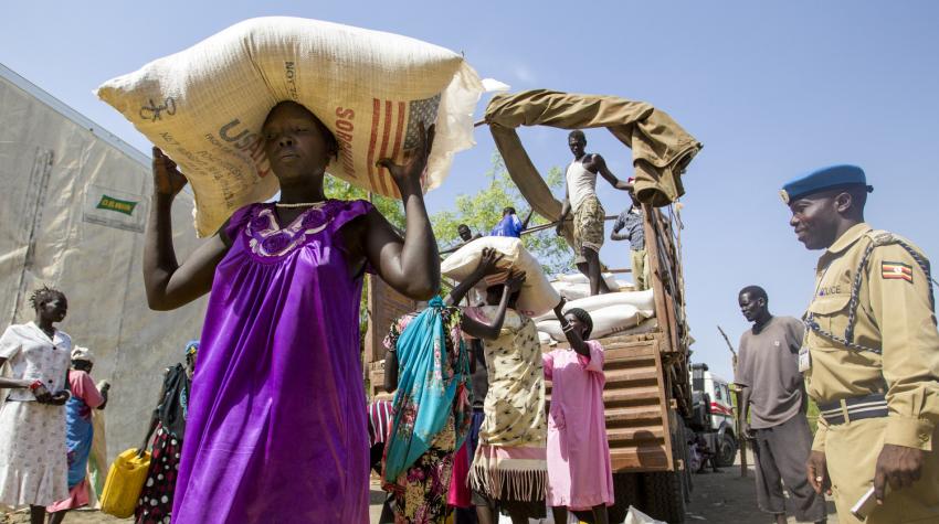 A Ugandan UN police officer based in Akobo, South Sudan, looks on as women are unloading food from a truck at a World Food Programme warehouse. 