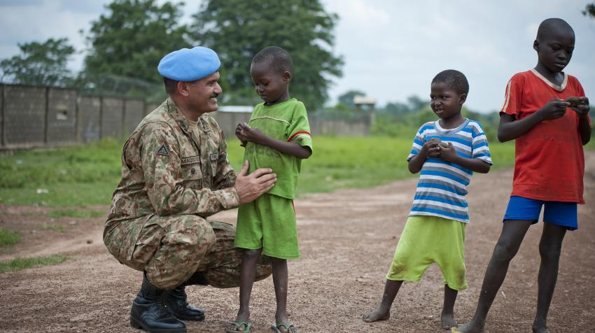 UN Military Adviser for Peacekeeping Operations smiling with three children of the town of Kaga Bandora during his visit to Central African Republic. 