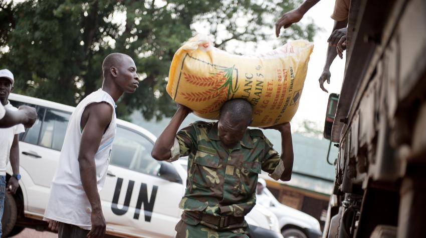 A soldier helping unload a bag of rice on his back at one of the camps for ex-combatants. 