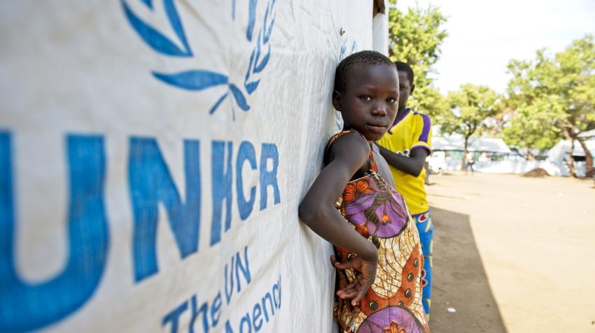 A young girl and a boy are leaning against one of the UNHCR settlement buildings in Northern Uganda. 