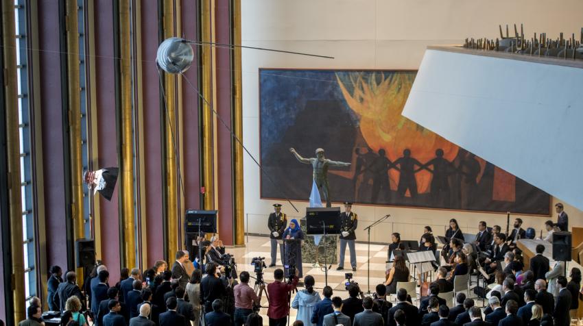 View of a medium-sized open space in the Visitors' Lobby with a huge painting on the wall and a statute. 