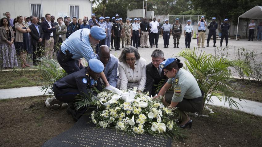 Several people in the center are laying white flowers to commemorate the 8th anniversary of the deadly earthquake in Haiti. 