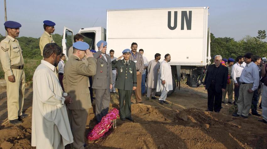 Military staff and other mourners are commemorating at the burial site of the UN staff and his son who were killed during the Pakistan Quake. 