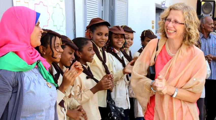 Inger smiles at a line of girls who are smiling back.