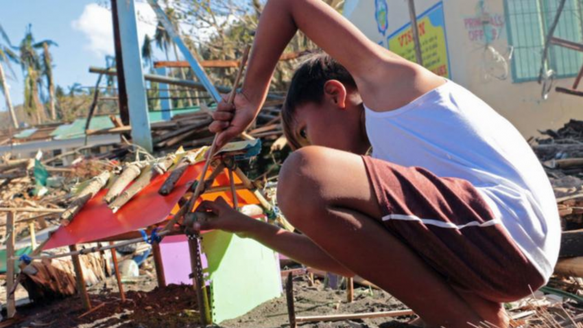 A boy makes a small house using plastic and debris. His home was completely swept away when Typhoon Goni hit the Philippines in November 2020.